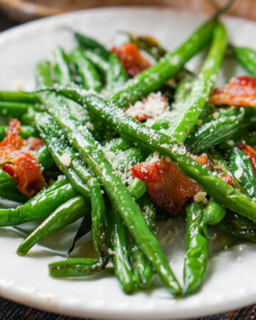 closeup of a white plate with green beans and bacon